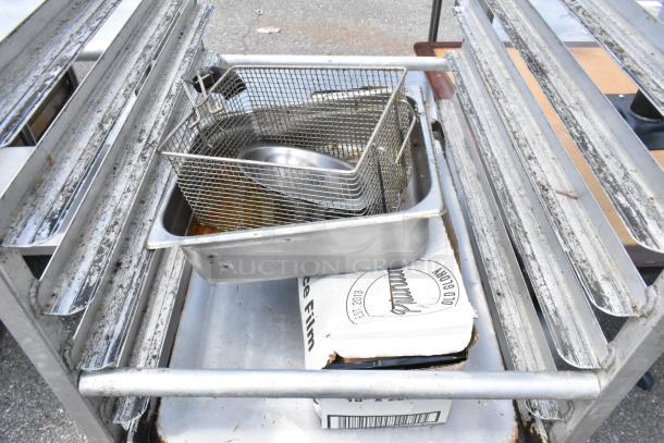 Metal commercial pan transport rack on casters, includes 12 baking pans, used condition, visible wear and rust.