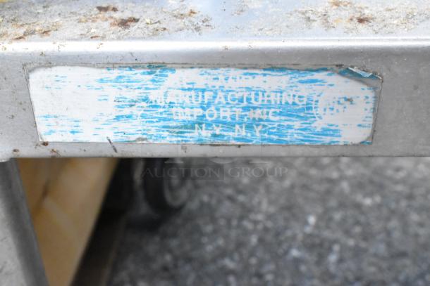 Stainless steel table with metal under shelf on commercial casters. Label indicates manufacturing in NYC. Used condition.