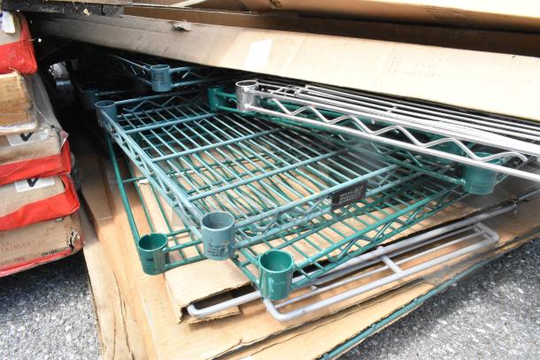 Pallet of brand new scratch and dent green Metro SWS18K3 wire shelves stacked on cardboard.