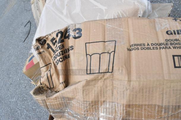 Cardboard box with visible wear and tear, marked with "15243" and glassware illustration. Contains scratch and dent items including a shelf kit, aluminum trays, and stock pot.