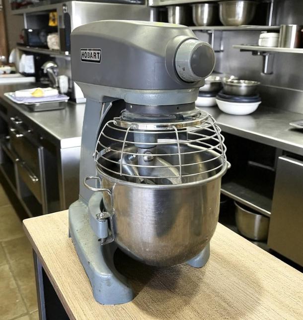 Hobart stand mixer in used condition, featuring a stainless steel bowl, safety guard, and sturdy metal body. Model 136 visible.