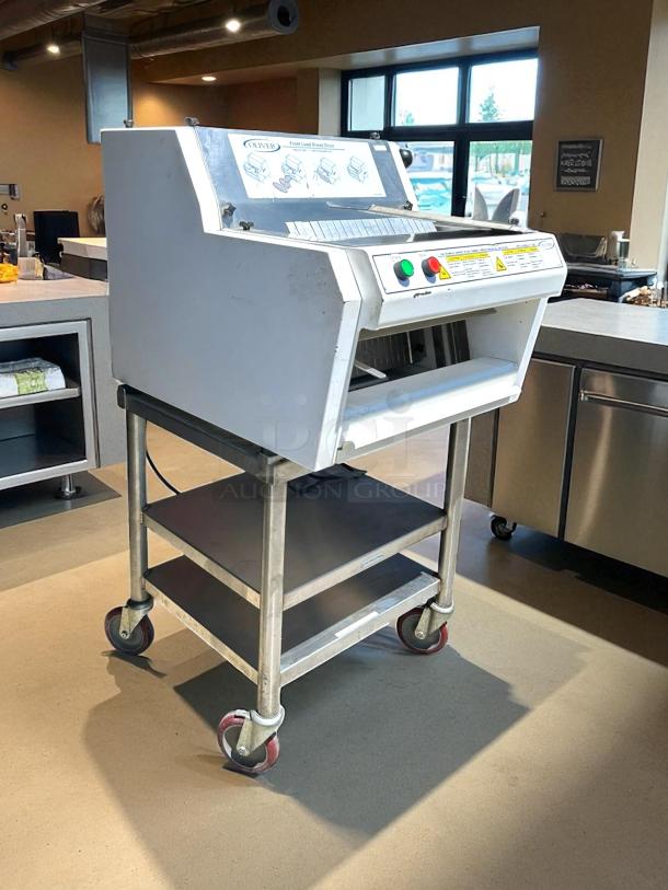 Oliver bread slicer on wheeled stand, well-maintained. Features include front load design, control buttons, and safety labels.