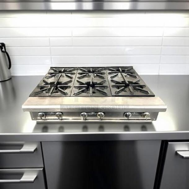 Commercial gas cooktop with six burners, stainless steel finish. Features durable control knobs and black grates, excellent condition.