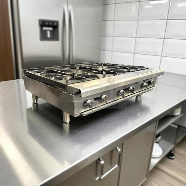 Stainless steel commercial countertop gas range with four burners and control knobs, in excellent condition.