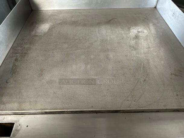 Metal tray with high edges, showing signs of wear and discoloration, likely used, made of steel. No visible labels or markings.
