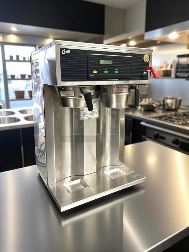 Curtis coffee brewer, dual spout, stainless steel, digital display, excellent condition, commercial kitchen setting.