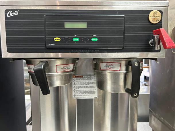 Curtis D1000GT coffee brewer with dual stainless steel dispensers, digital controls, and warning labels. Good condition.