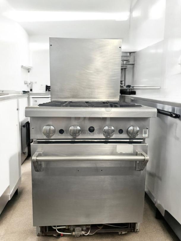 Commercial-grade 4-burner gas range with standard oven, stainless steel, excellent condition, fully tested and working.