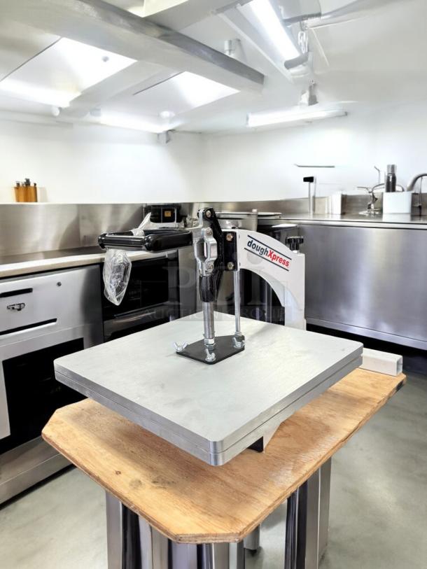 DoughXpress manual pizza dough press, excellent condition, fully tested and working, with sturdy construction in a professional kitchen.