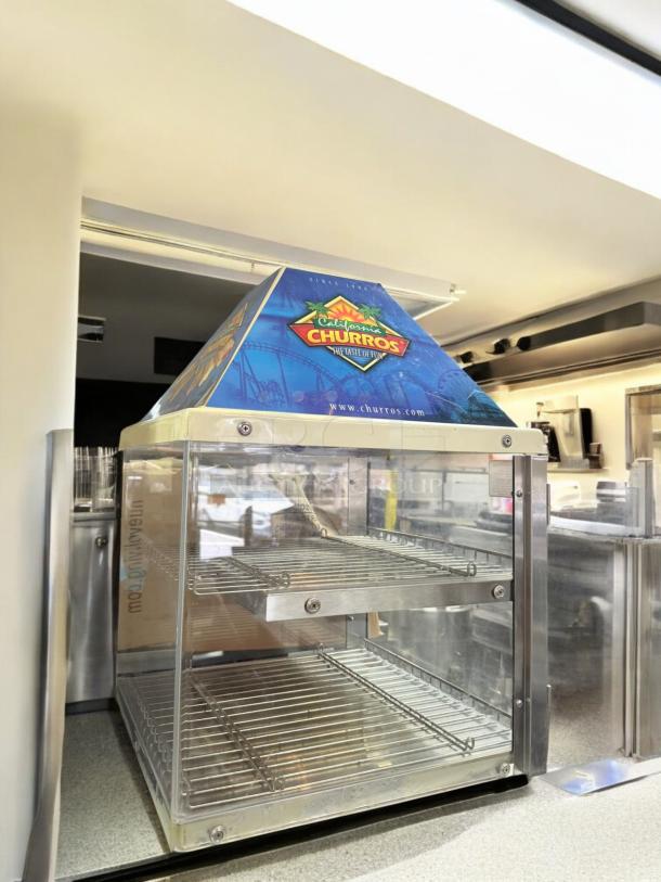 California Churros countertop warmer display case in excellent condition. Features clear glass panels, metal racks, branded top, 120V.