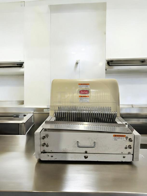 Berkel MB 1/2 bread slicer in excellent condition, 115V. Features sharp blades, visible warning labels, fully tested and working.