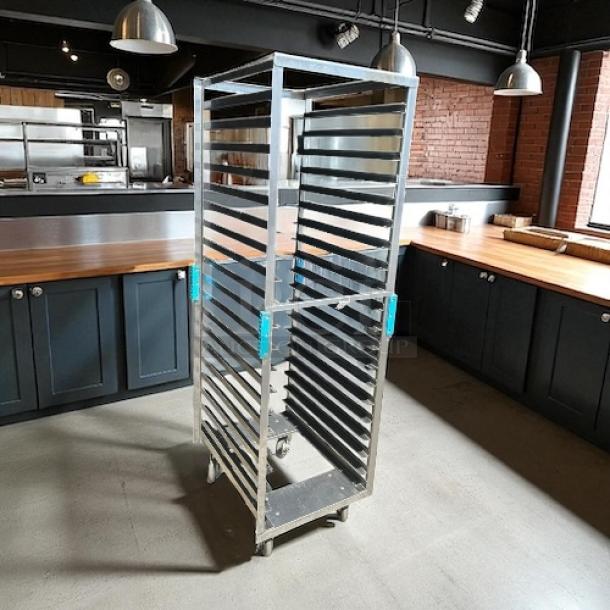 "Like New" bakery sheet pan rack with smooth rolling casters, stainless steel construction, multiple sheet slots in a modern kitchen.