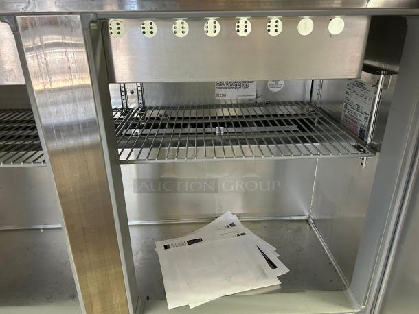 Continental Refrigerator SW48-N-18M prep table, interior view. Shows wire shelves, labels with specs, and resting papers.