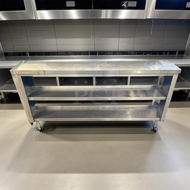 Stainless steel 73" custom-made table with three open shelves, sturdy metal frame, and caster wheels; in good condition.