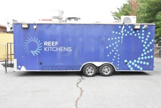 Blue food trailer with "REEF KITCHENS" logo, equipped with a grease hood, fryers, coolers, freezers, prep tables, and a range. Sold with clear title.