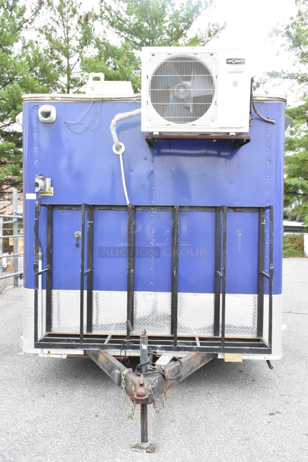 Mobile food trailer with blue exterior, featuring an air conditioning unit, metal hitch, and equipment hatch. Ready for operation.