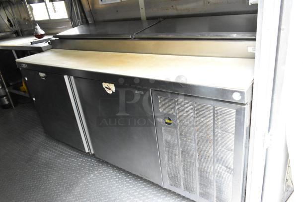 Mobile kitchen interior showing prep tables, coolers, and stainless steel surfaces in a former Popeyes food trailer.