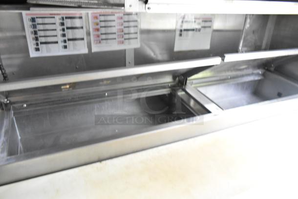 Mobile kitchen interior with open stainless steel prep tables, shelving, and instructional charts for food preparation.