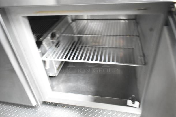 Stainless steel food trailer interior; open fridge view with metal shelves, diamond plate flooring visible.