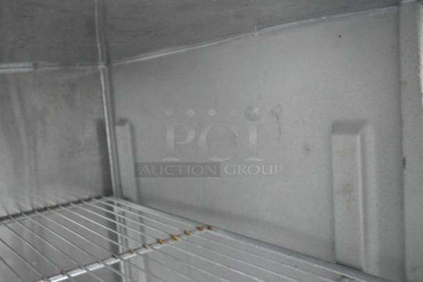 Interior view of a stainless steel cooler inside a mobile kitchen trailer, showing metal shelving and clean surfaces.