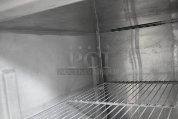 Interior view of a stainless steel cooler in a food trailer, featuring wire shelving and clean surfaces.