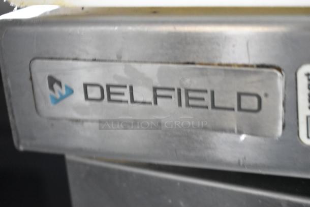 Metallic surface with a Delfield logo tag, indicating the maker of a cooler or freezer in the food trailer.