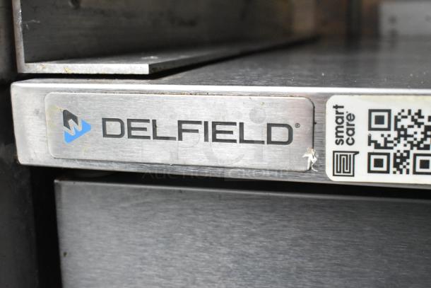 Delfield metal label on a food trailer appliance, featuring brand logo and QR code for "smart care."
