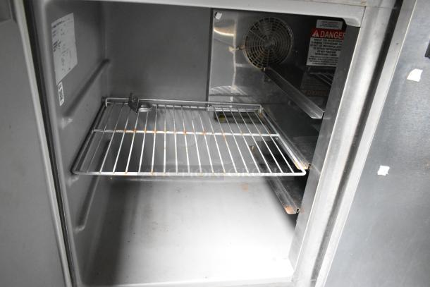 Interior of a food trailer appliance showing a metal rack and a ventilation fan. Warning label visible on the side.