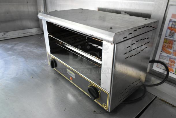 Commercial countertop oven inside a former Popeyes food trailer, stainless steel, with dual knobs and ventilation slots.