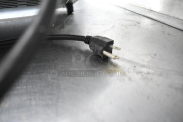 Power cord on a metal surface, part of the kitchen equipment in a fully outfitted Popeyes food trailer.