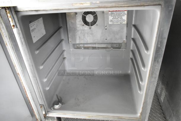 Interior view of a food trailer cooler showing clean, metal shelves and a visible warning label. Suitable for mobile kitchen use.