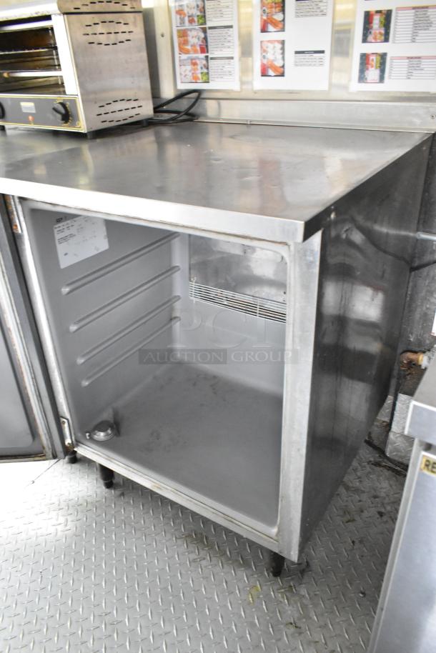 Fully outfitted food trailer interior with stainless steel prep tables, appliances, and open refrigerator in good condition.