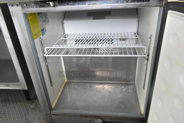 Interior view of a food trailer cooler with shelving and instructional labels, showing space for storage.