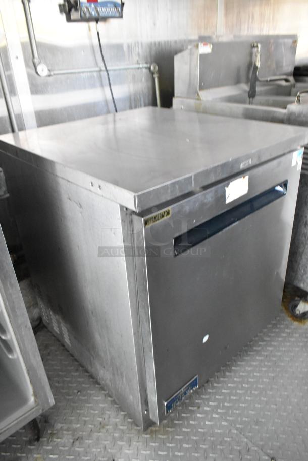 Mobile kitchen refrigerator on textured metal flooring, labeled "Refrigerator," part of a Popeyes food trailer setup.