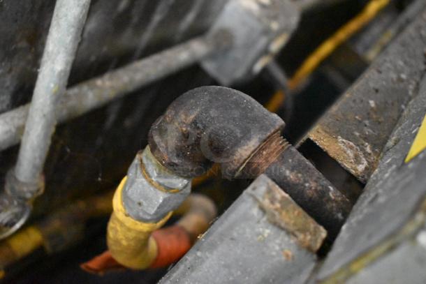 Close-up view of a pipe connection inside a food trailer. Slight rust visible on metal components.