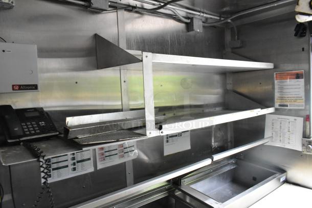 Fully equipped Popeyes food trailer interior with stainless steel shelves, Altronix box, wall-mounted phone, and prep area.