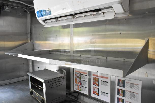 Former Popeyes food trailer interior with stainless steel prep area, ventilation, and appliance. Includes menus on the wall.