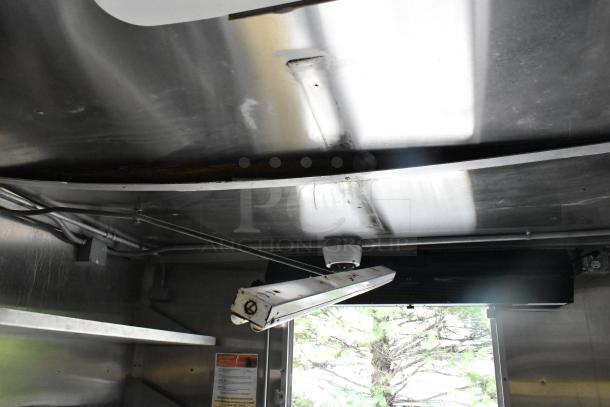 Interior of a fully outfitted former Popeyes food trailer, featuring a grease hood and lighting fixture.