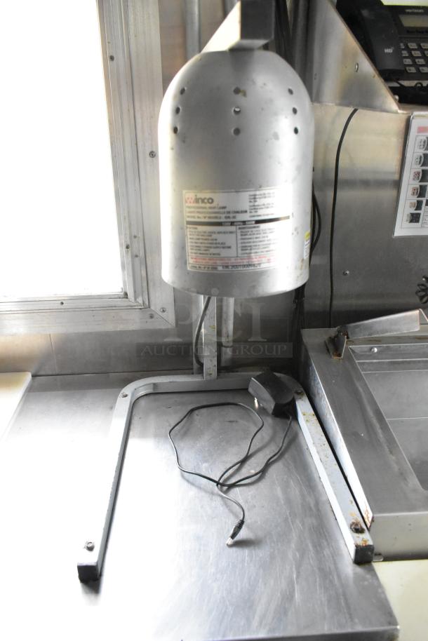 Fully outfitted mobile kitchen with stainless steel surfaces, visible wiring, and a labeled Winco heat lamp. Ideal for startups.