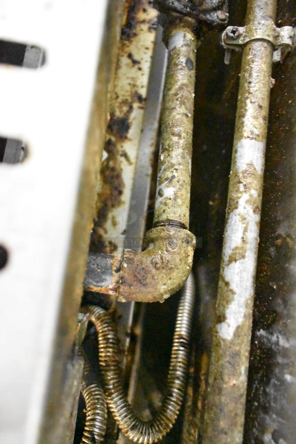 Close-up of a used metal pipe and fittings in a food trailer, showing rust and wear, part of a mobile kitchen setup.