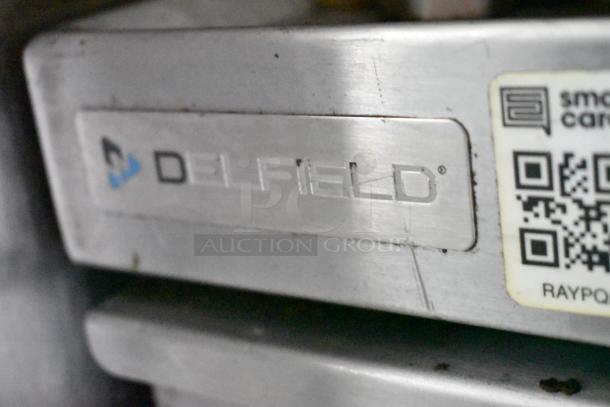 Delfield appliance in a food trailer, showing branded metal label and QR code sticker, indicating commercial quality.