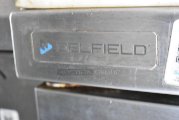 Label on Delfield cooler or freezer, indicating brand on food trailer appliance. Item includes various cooking equipment.