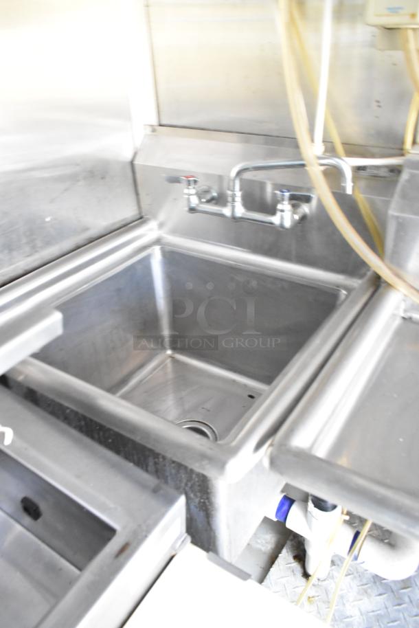 Stainless steel sink in a former Popeyes food trailer with faucet and pipe connections, suitable for mobile kitchen use.