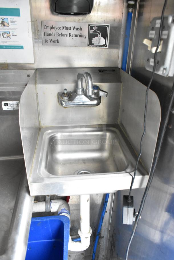 Stainless steel sink with faucet in a food trailer. Sign reads "Employee Must Wash Hands Before Returning To Work."