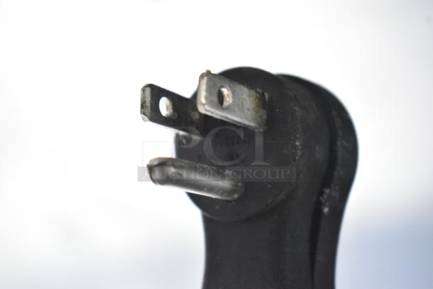 Close-up of an electrical plug with prongs, slightly rusted, and a round black base.