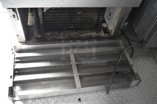Close-up of a metal grate inside a former Popeyes food trailer, showing its condition and detailing.