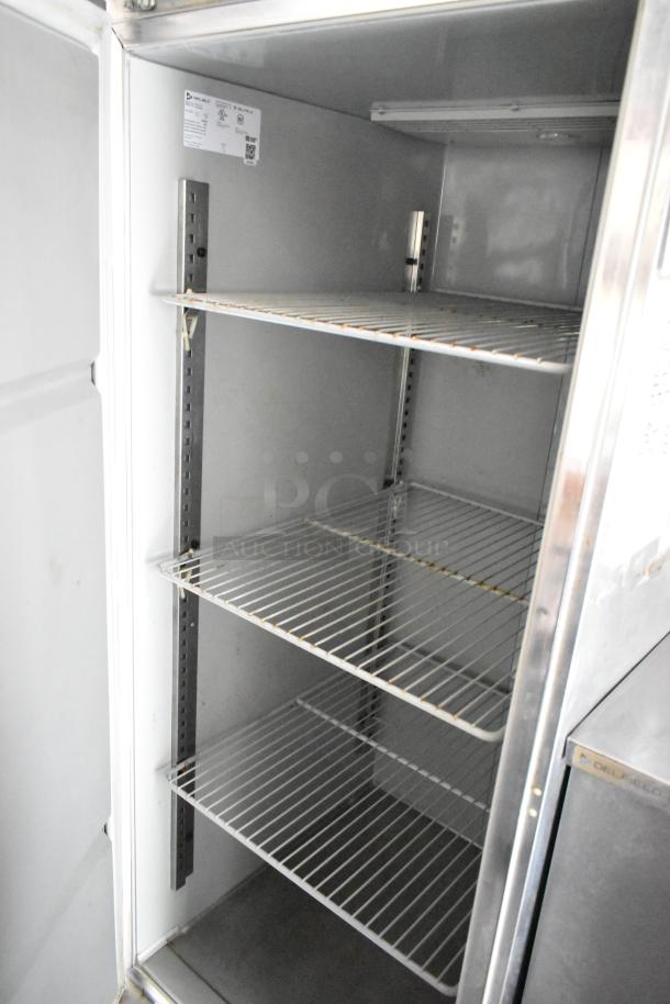 Interior of a commercial cooler featuring three wire shelves. Model tag indicates "Delfield" brand with specifications.