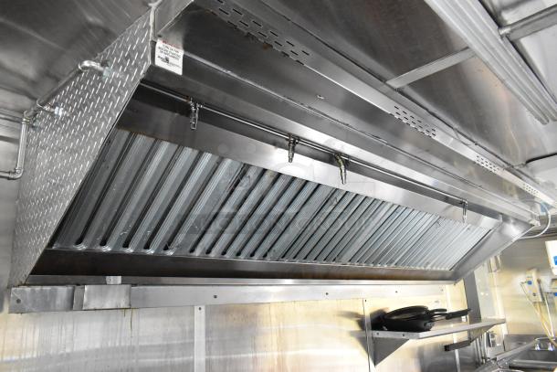 Industrial grease hood inside a fully outfitted food trailer kitchen, featuring stainless steel construction and venting system.