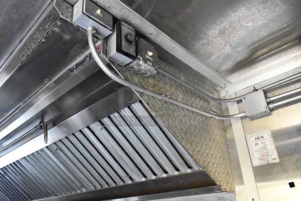 Alt text: Stainless steel grease hood in a former Popeyes food trailer, featuring electrical controls and safety certification label.