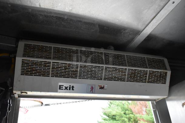 Interior of a mobile kitchen showing a wall-mounted exhaust fan with "Exit" label and safety signage in used condition.